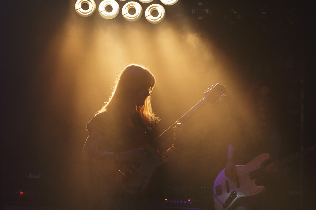 Concert photography of the guitarist of Lurch. Her silhouette is back-lit by yellow stage spot ligths.