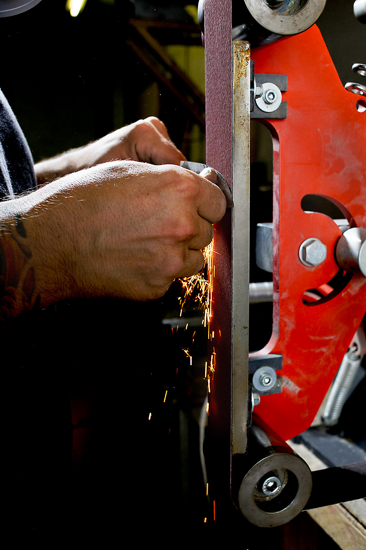 Close-up photography of a person sharpening a knife with a sanding belt.