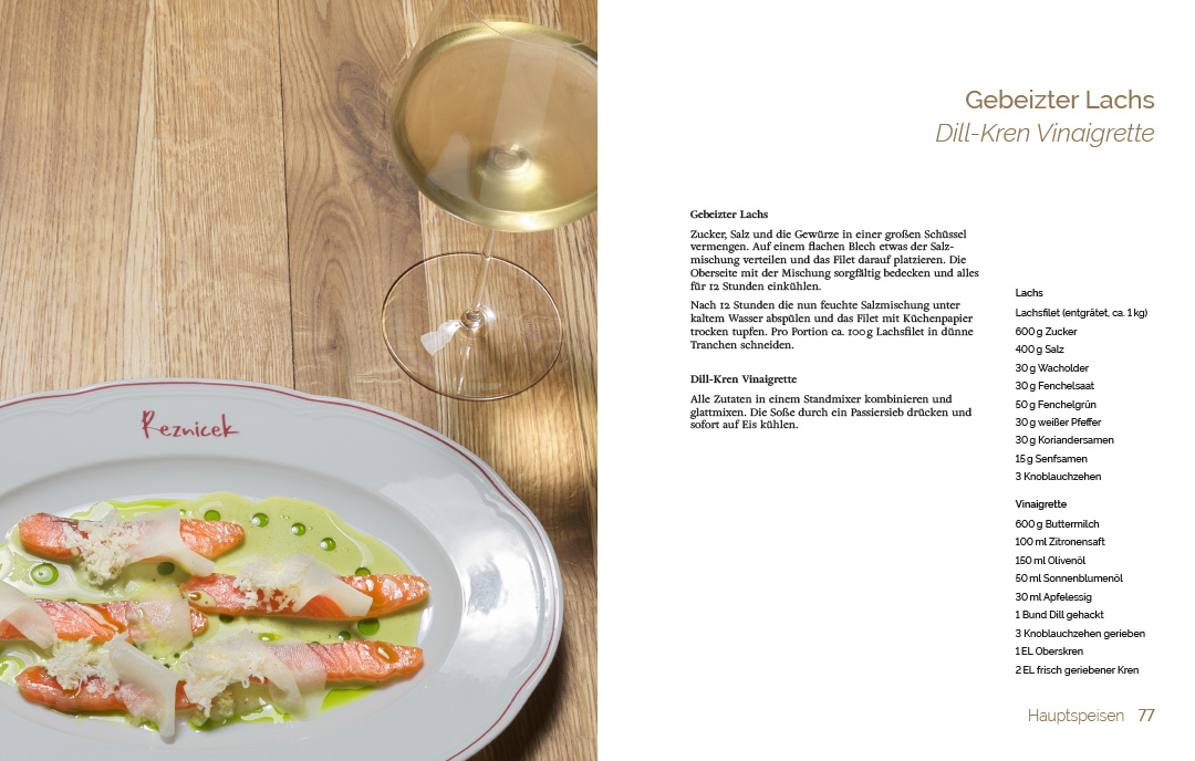 An image showing a spread of a cook book designed by Koen Smet for the Viennese restaurant Reznicek. The left page shows a salmon dish with a green vinaigrette. The right page shows the recipe for gebeitzer Lachs mit einer dill-kren Vinaigrette.