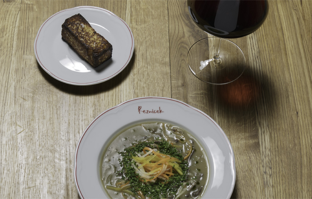 An image showing a spread of a cook book designed by Koen Smet for the Viennese restaurant Reznicek. The spread is a double-paged photography of a lamb dish.