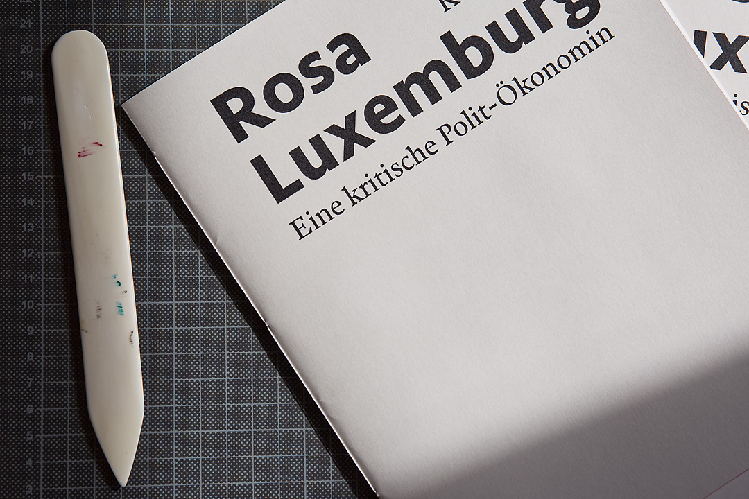 A close up photography of a brochure on Rosa Luxemburg by Koen Smet. It shows a white side sewn binding.