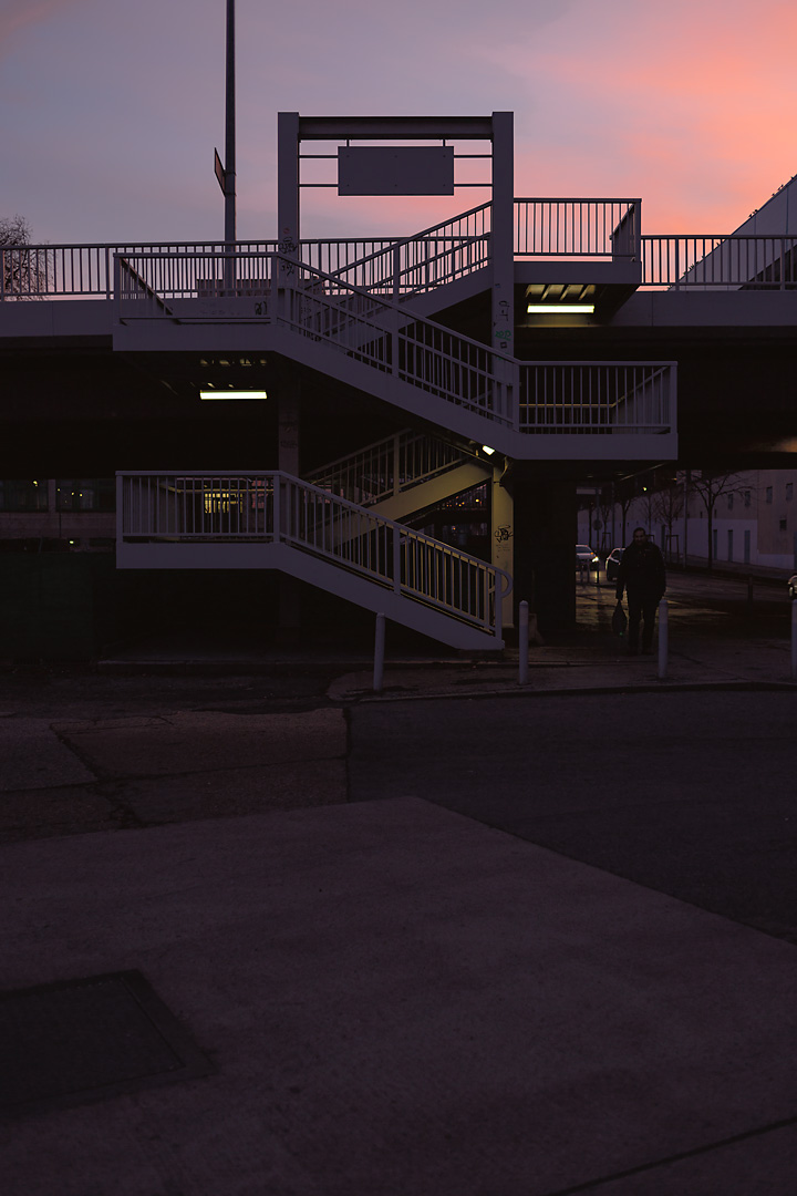 Streetphotography of the Spetterbruecke in Vienna. Against the backdrop of a pink evening sky the profile of a staircase is visible.