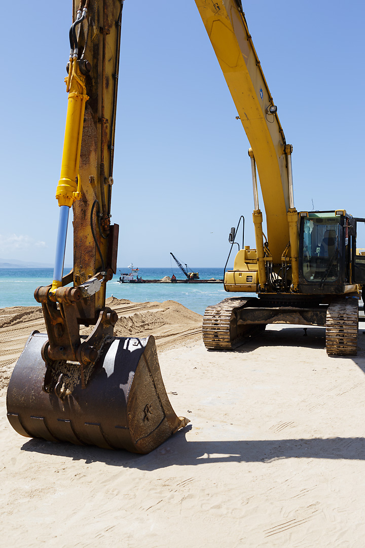 Streetphotography of a yellow excavator in the fishing harbour of Ericeira, Portugal.